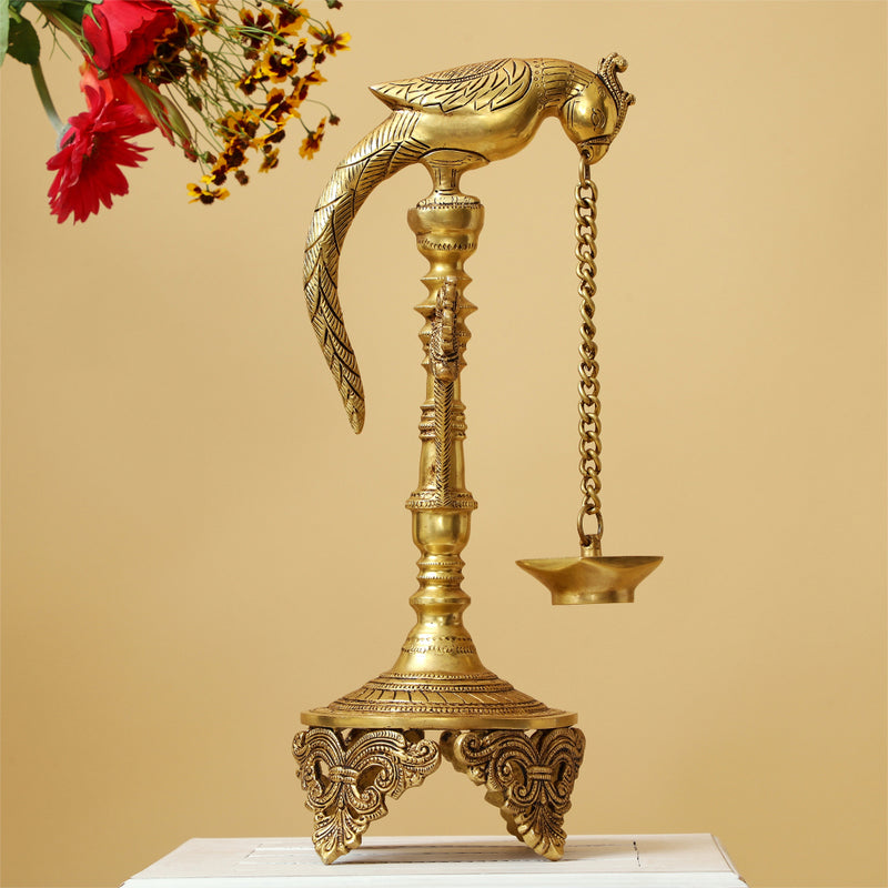 Brass peacock parrot Diya - exquisitely crafted brass oil lamp in the shape of a peacock with parrot motifs, golden finish, decorative home accent, fusion of elegance and vibrancy, traditional Indian Diya, emits a captivating and auspicious glow, perfect for festive occasions and religious ceremonies, enhances spiritual ambiance and decor with a touch of artistic brilliance.