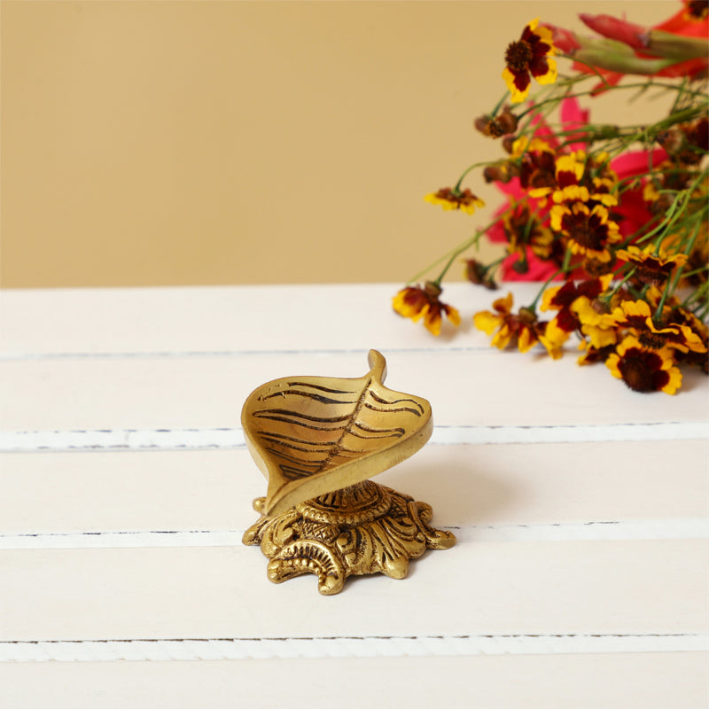 Brass Leaf Diya - elegantly crafted brass oil lamp in the shape of a leaf, golden finish, decorative home accent, inspired by nature's beauty, traditional Indian Diya, emits a soft and serene glow, ideal for religious ceremonies and festive occasions, enhances spiritual ambiance and decor with a touch of natural charm.