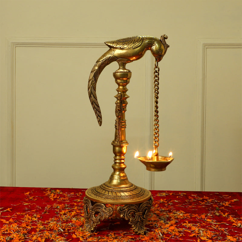 Brass peacock parrot Diya - exquisitely crafted brass oil lamp in the shape of a peacock with parrot motifs, golden finish, decorative home accent, fusion of elegance and vibrancy, traditional Indian Diya, emits a captivating and auspicious glow, perfect for festive occasions and religious ceremonies, enhances spiritual ambiance and decor with a touch of artistic brilliance.