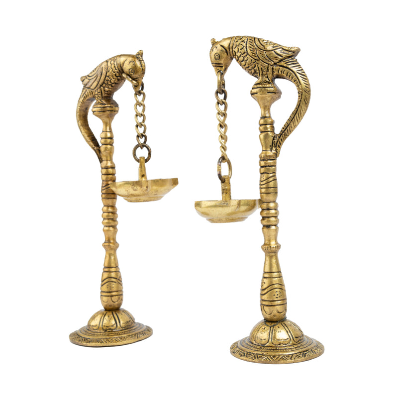 Brass peacock parrot Diya - exquisitely crafted brass oil lamp in the shape of a peacock with parrot motifs, golden finish, decorative home accent, fusion of elegance and vibrancy, traditional Indian Diya, emits a captivating and auspicious glow, perfect for festive occasions and religious ceremonies, enhances spiritual ambiance and decor with a touch of artistic brilliance.