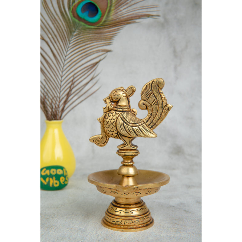 Brass peacock parrot Diya - exquisitely crafted brass oil lamp in the shape of a peacock with parrot motifs, golden finish, decorative home accent, fusion of elegance and vibrancy, traditional Indian Diya, emits a captivating and auspicious glow, perfect for festive occasions and religious ceremonies, enhances spiritual ambiance and decor with a touch of artistic brilliance.