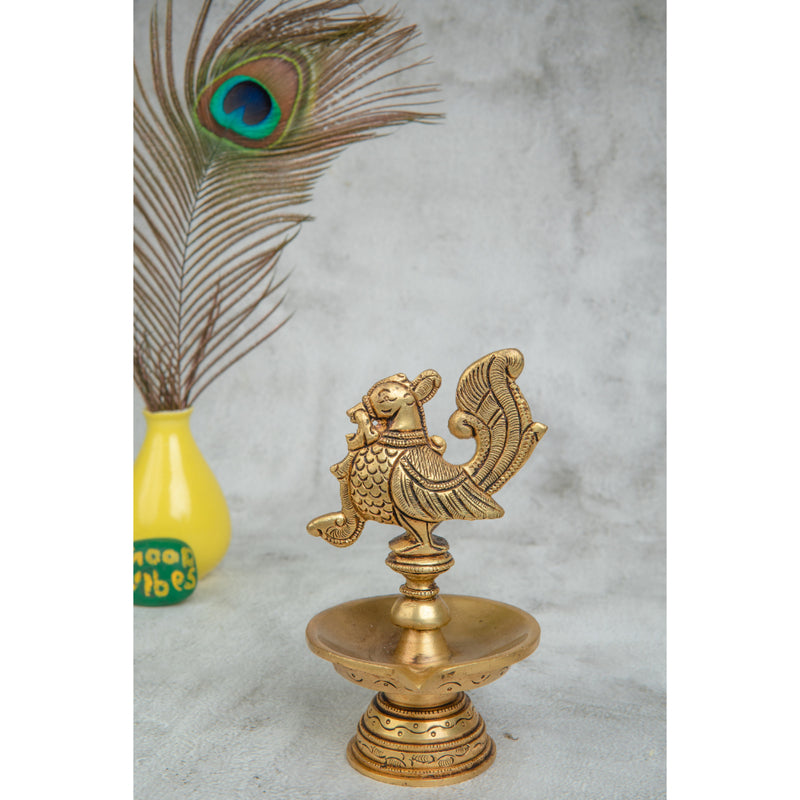 Brass peacock parrot Diya - exquisitely crafted brass oil lamp in the shape of a peacock with parrot motifs, golden finish, decorative home accent, fusion of elegance and vibrancy, traditional Indian Diya, emits a captivating and auspicious glow, perfect for festive occasions and religious ceremonies, enhances spiritual ambiance and decor with a touch of artistic brilliance.