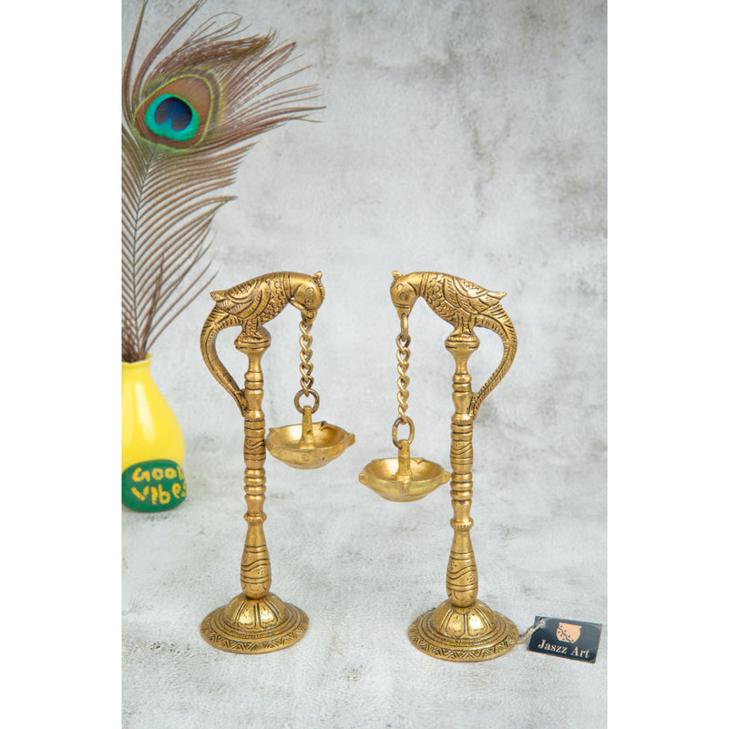 Brass peacock parrot Diya - exquisitely crafted brass oil lamp in the shape of a peacock with parrot motifs, golden finish, decorative home accent, fusion of elegance and vibrancy, traditional Indian Diya, emits a captivating and auspicious glow, perfect for festive occasions and religious ceremonies, enhances spiritual ambiance and decor with a touch of artistic brilliance.