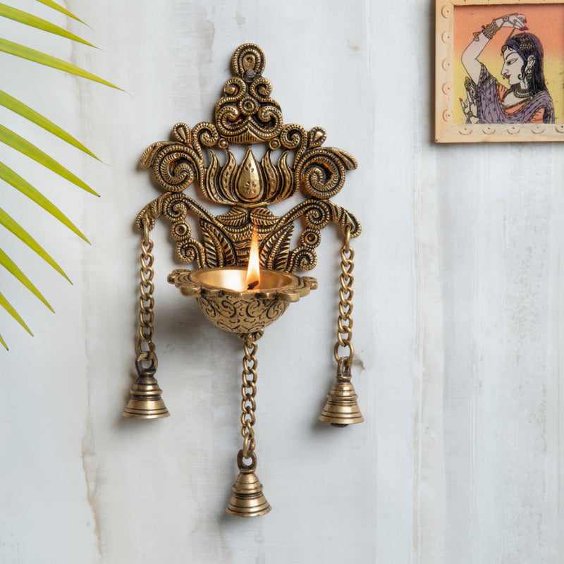 Brass Wall Diya - intricately designed brass oil lamp for wall mounting, golden finish, decorative home accent, traditional Indian Diya, emits a warm and inviting glow, ideal for enhancing wall decor and creating an ambiance of serenity, perfect for religious ceremonies and festive occasions, adds a touch of traditional charm to interior spaces.