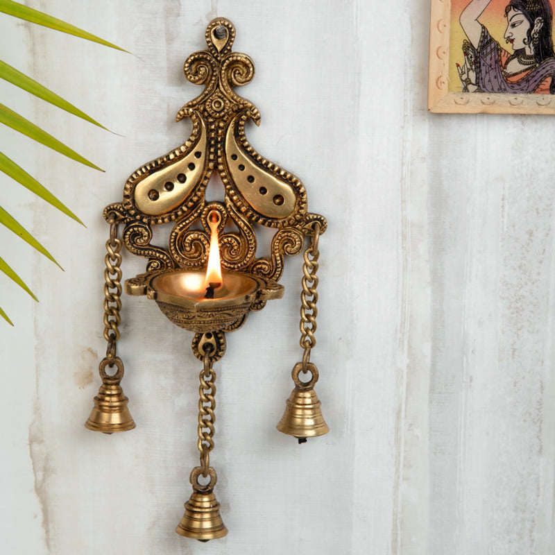 Brass Wall Diya - intricately designed brass oil lamp for wall mounting, golden finish, decorative home accent, traditional Indian Diya, emits a warm and inviting glow, ideal for enhancing wall decor and creating an ambiance of serenity, perfect for religious ceremonies and festive occasions, adds a touch of traditional charm to interior spaces.