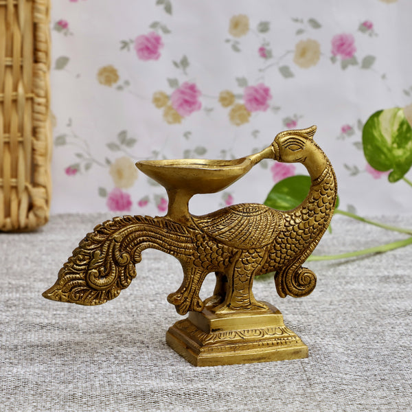 Brass peacock parrot Diya - exquisitely crafted brass oil lamp in the shape of a peacock with parrot motifs, golden finish, decorative home accent, fusion of elegance and vibrancy, traditional Indian Diya, emits a captivating and auspicious glow, perfect for festive occasions and religious ceremonies, enhances spiritual ambiance and decor with a touch of artistic brilliance.