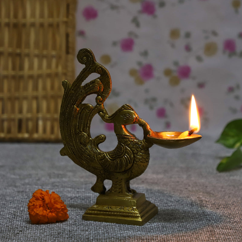 Brass peacock parrot Diya - exquisitely crafted brass oil lamp in the shape of a peacock with parrot motifs, golden finish, decorative home accent, fusion of elegance and vibrancy, traditional Indian Diya, emits a captivating and auspicious glow, perfect for festive occasions and religious ceremonies, enhances spiritual ambiance and decor with a touch of artistic brilliance.