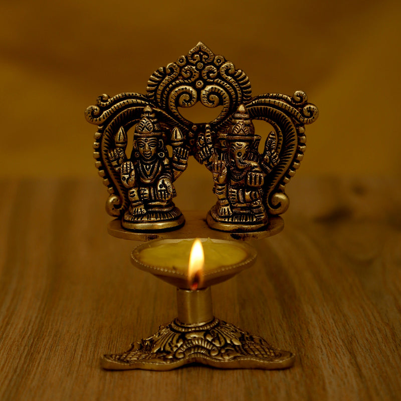 Brass Ganesha Lakshmi Diya - exquisitely crafted brass oil lamp featuring Lord Ganesha and Goddess Lakshmi, golden finish, decorative home accent, symbolizes prosperity and divine blessings, traditional Indian Diya, emits a radiant and auspicious glow, perfect for religious ceremonies and festive occasions, enhances spiritual ambiance and decor with the blessings of Ganesha and Lakshmi.